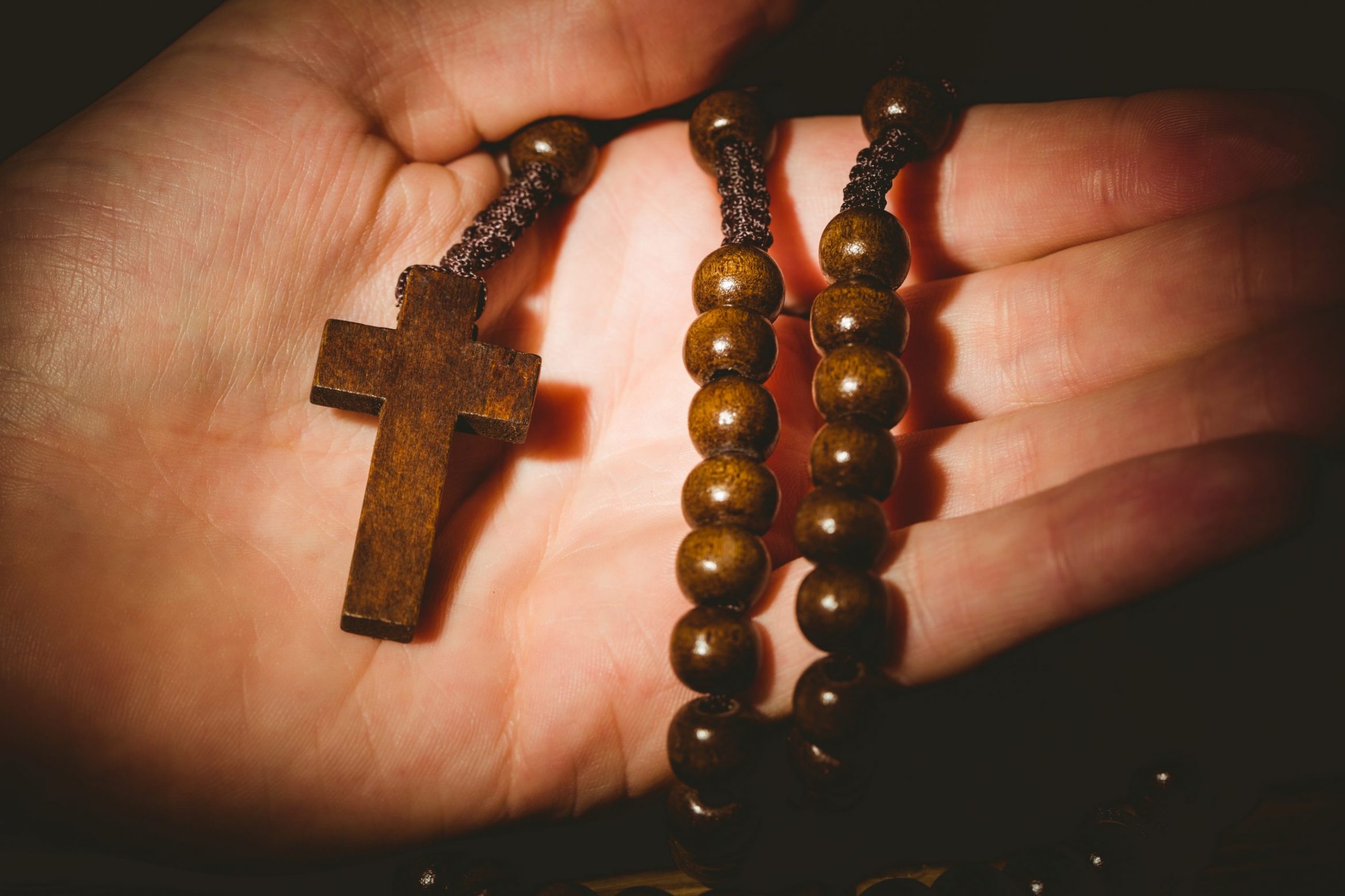 hand-holding-wooden-rosary-beads-scaled.jpg