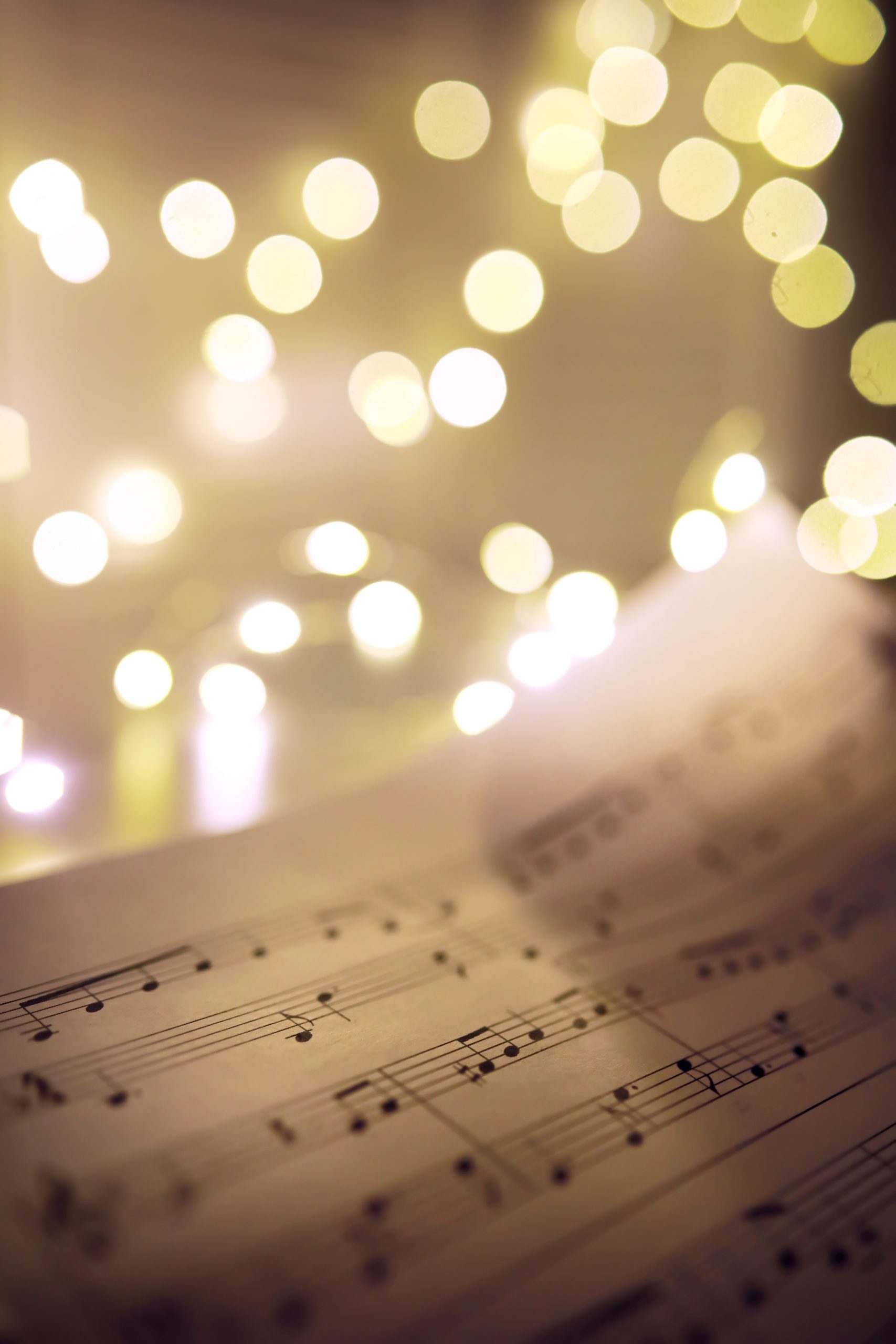 old-sheet-with-christmas-music-notes-as-background-against-blurred-lights-christmas-music-concept-scaled.jpg